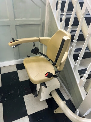 A motorised stairlift installed on a carpeted staircase, helping a homeowner move safely and independently between floors