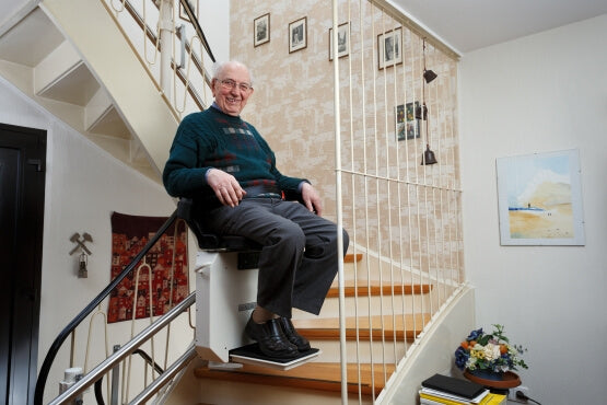 Elderly man smiling while using his stairlift at home to help with mobility. 