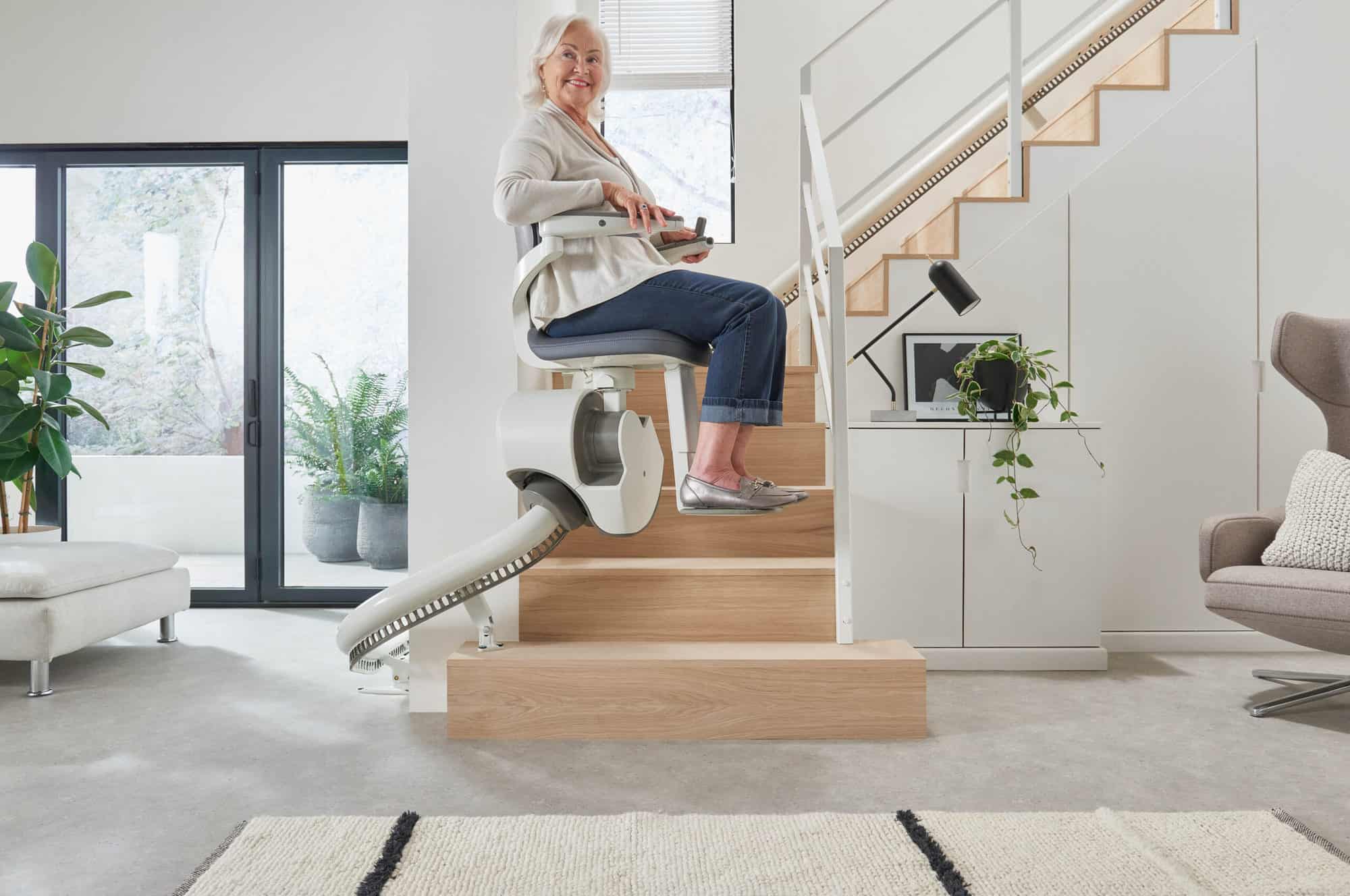 Flow X stairlifts model in use on a curved staircase in a bright home