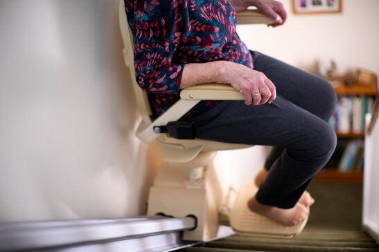 Person using a home stairlift on a staircase, highlighting the importance of regular stairlift maintenance and safety checks.