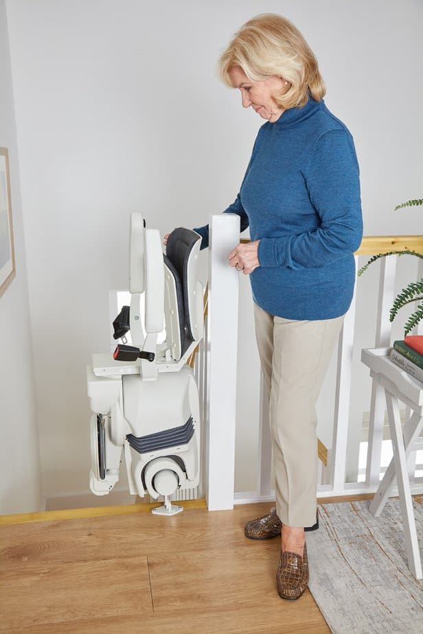 Woman standing at the top of the stairs next to a folded used stairlift in a modern home