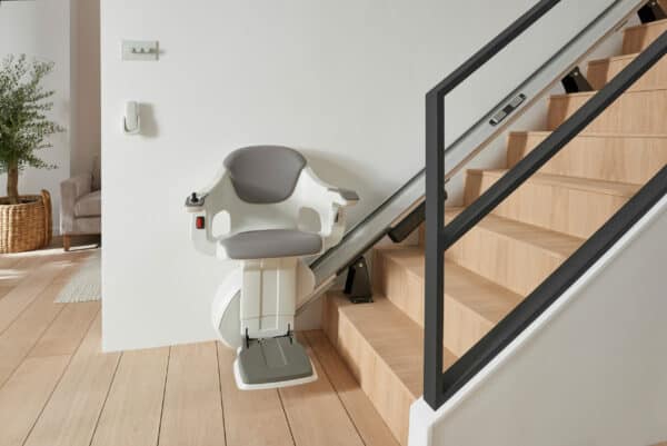 A Thyssen Homeglide stairlift at the foot of the stairs, ready to go