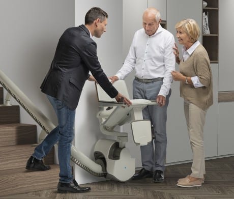 A man shows a couple how a stairlift works